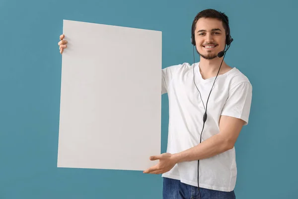 Male technical support agent with blank poster on blue background