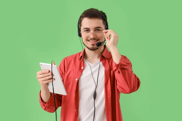 Male technical support agent with tablet computer on green background