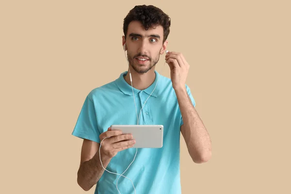 Νεαρός Άνδρας Tablet Υπολογιστή Και Ακουστικά Μπεζ Φόντο — Φωτογραφία Αρχείου