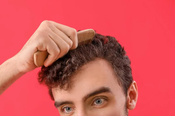 Молодой Брюнетка Мужчина Расчесывает Волосы Красном Фоне Крупным Планом — стоковое фото