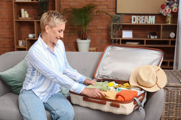 stock image Mature woman packing suitcase on sofa at home