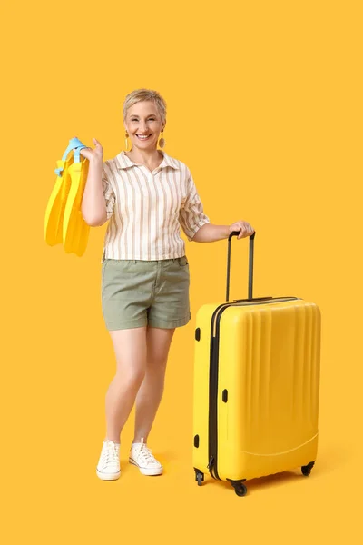 stock image Mature woman with flippers and suitcase on yellow background