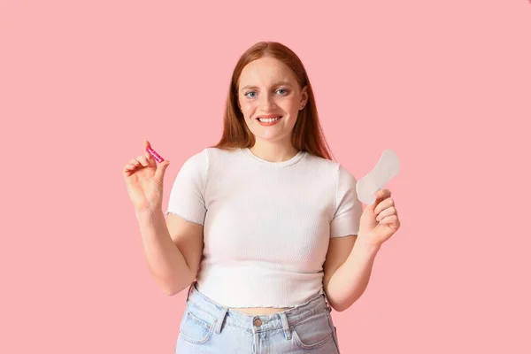 月経パッドとピンクの背景にタンポンを持つ若い女性 — ストック写真