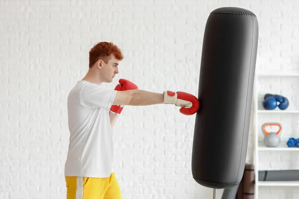 年轻红头发拳击手在体育馆里打沙袋 — 图库照片