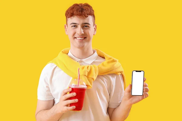 Mladý Ryšavý Muž Šálkem Limonády Mobilní Telefon Žlutém Pozadí — Stock fotografie