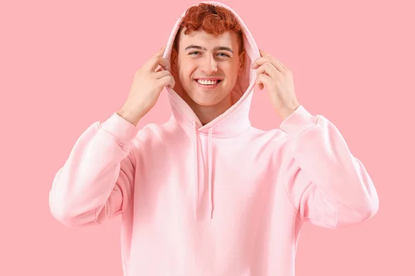 ピンクの背景にフーディーの若い赤毛の男 — ストック写真
