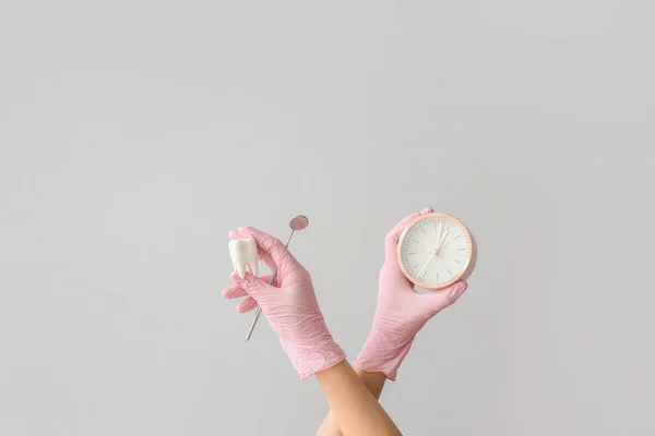 歯の鏡 歯のモデル グレーの背景に時計が付いている女性の医者の手 — ストック写真
