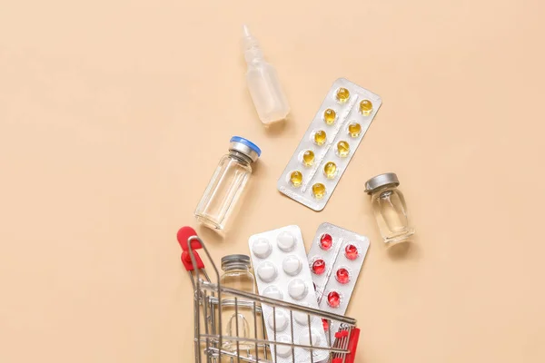 ベージュの背景に異なる薬とミニショッピングカート — ストック写真