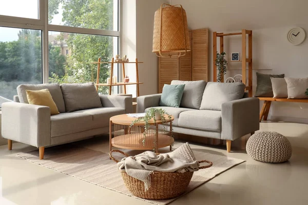 Interior of light living room with cozy grey sofas and wooden coffee table
