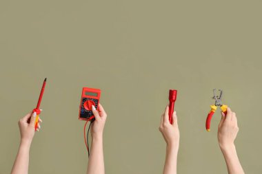 Electrician hands with tools on green background