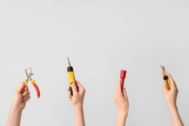 Electrician hands with tools on grey background