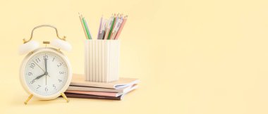 Açık arkaplan üzerinde okul kırtasiyesi ve metin için alanı olan alarmlı saat