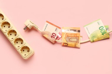 Avro banknotları ve pembe arka planda elektrik prizi. Elektrik faturası kavramı