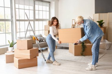 Taşındığı gün odada karton kutu taşıyan genç bir çift.