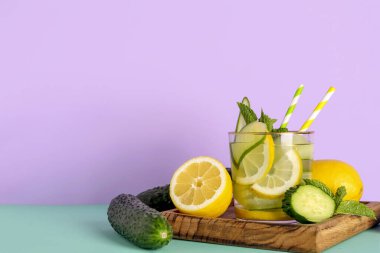 Bir bardak salatalıklı limonata ve renkli arkaplanda nane şekeri.