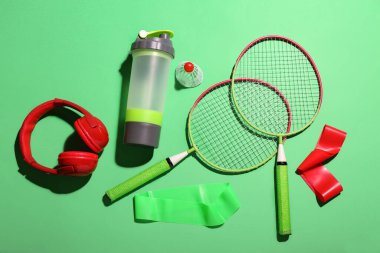 Spor ekipmanları ve yeşil arka planda bir şişe su ile kompozisyon