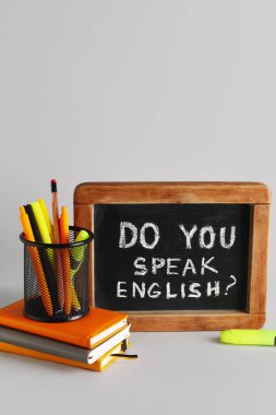 Soru ile kırtasiye ve karatahta İngilizce konuşuyor musunuz? gri arkaplanda