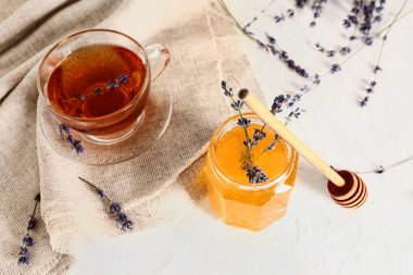 Tatlı lavantalı kavanoz bal ve beyaz arka planda bir fincan çay.