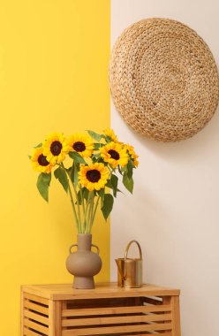 Çekmecede ayçiçekli vazo ve sulama kutusu var.