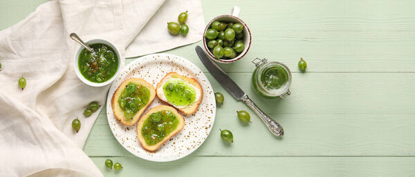 Plate with tasty bread slices and gooseberry jam on green wooden background. Banner for design
