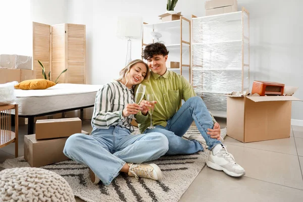 Young couple drinking champagne in bedroom on moving day