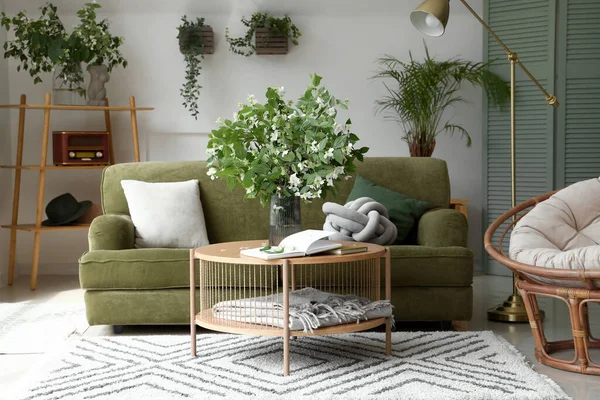 stock image Interior of light living room with green sofa and blooming jasmine flowers on coffee table