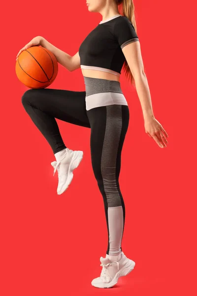 若いです女性でスポーツウェアとボールで赤い背景 — ストック写真