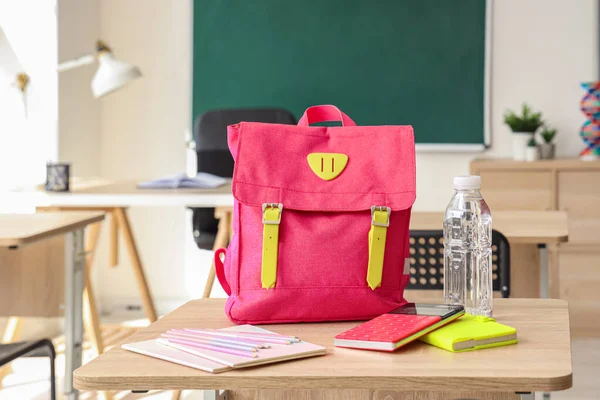 粉红校服背包 课桌上放着文具和瓶装水 — 图库照片