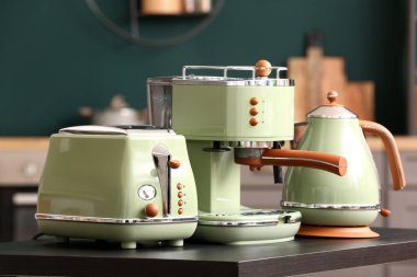 Elektrik ısıtıcısı, kahve makinesi ve tost makinesi mutfakta siyah masada.