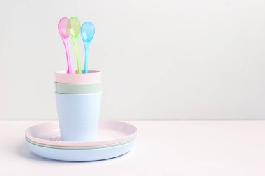 Beyaz masadaki bebek için kaşıklı ve fincanlı tabaklar.