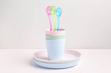 Beyaz masadaki bebek için kaşıklı ve fincanlı tabaklar.