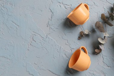 Bebek için fincanları olan çaydanlık ve grunge grisi arka planda okaliptüs dalı