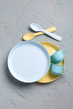 Gri arkaplanda tabakları ve kaşıkları olan bardaklar