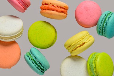 Flying sweet macaroons on grey background clipart