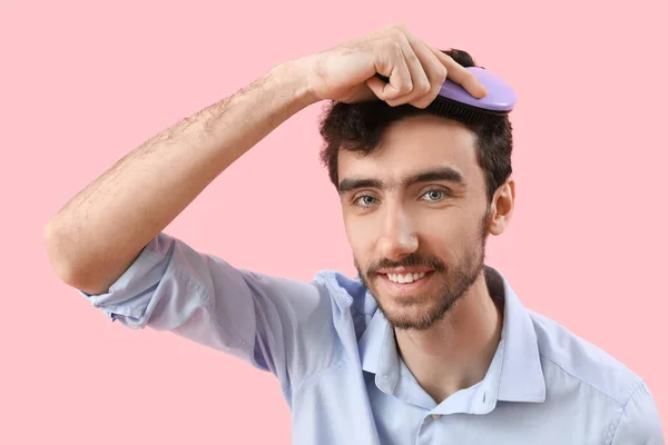 若いブルネットの男はピンクの背景に髪をブラッシング クローズアップ — ストック写真