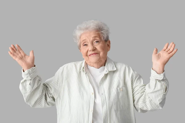 Senior Vrouw Shrugging Grijze Achtergrond — Stockfoto