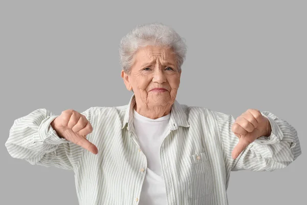 Старшая Женщина Показывает Большие Пальцы Вниз Сером Фоне — стоковое фото