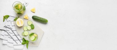 Hafif grunge arka planında salatalıklı soğuk limonata bardağı ve sürahi.