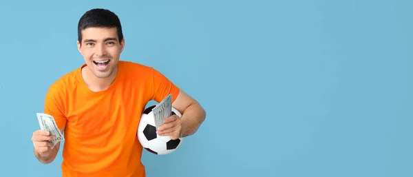 サッカーボールとテキストのためのスペースを持つ青い背景でお金を持つ幸せな若者 スポーツベットコンセプト — ストック写真