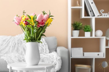 Oturma odasındaki masada bahar çiçekleri olan vazo.