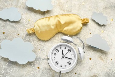 Composition with alarm clock, sleeping mask and paper clouds on grunge background. World Sleep Day concept