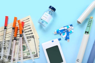 Glukometreyle insülin, tükenmez kalemler, şırıngalar ve mavi arka planda para. Pahalı tıp konsepti