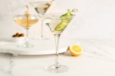 Beyaz masada bir bardak lezzetli martini ve limon.