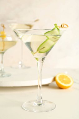 Beyaz masada bir bardak lezzetli martini ve limon.