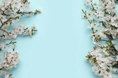 Mavi arkaplanda çiçek açan dallardan oluşan çerçeve