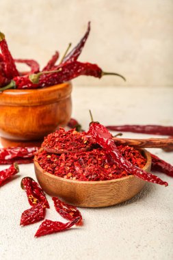 Ahşap kaseli kompozisyon ve beyaz arka planda kuru sıcak kırmızı biber havanı.