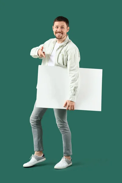 Yakışıklı Adam Yeşil Arka Plandaki Büyük Boş Postere Işaret Ediyor — Stok fotoğraf