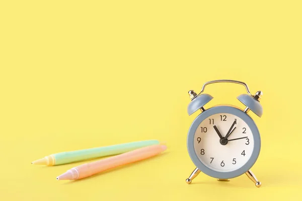 Sarı Zemin Üzerindeki Alarm Saati Kalemler — Stok fotoğraf