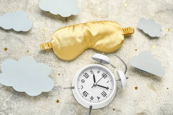 Composition with alarm clock, sleeping mask and paper clouds on grunge background. World Sleep Day concept