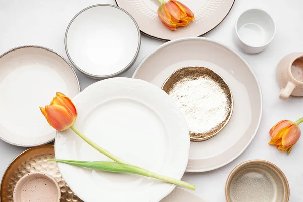 stock image Composition with different clean dishes and tulip flowers on white background